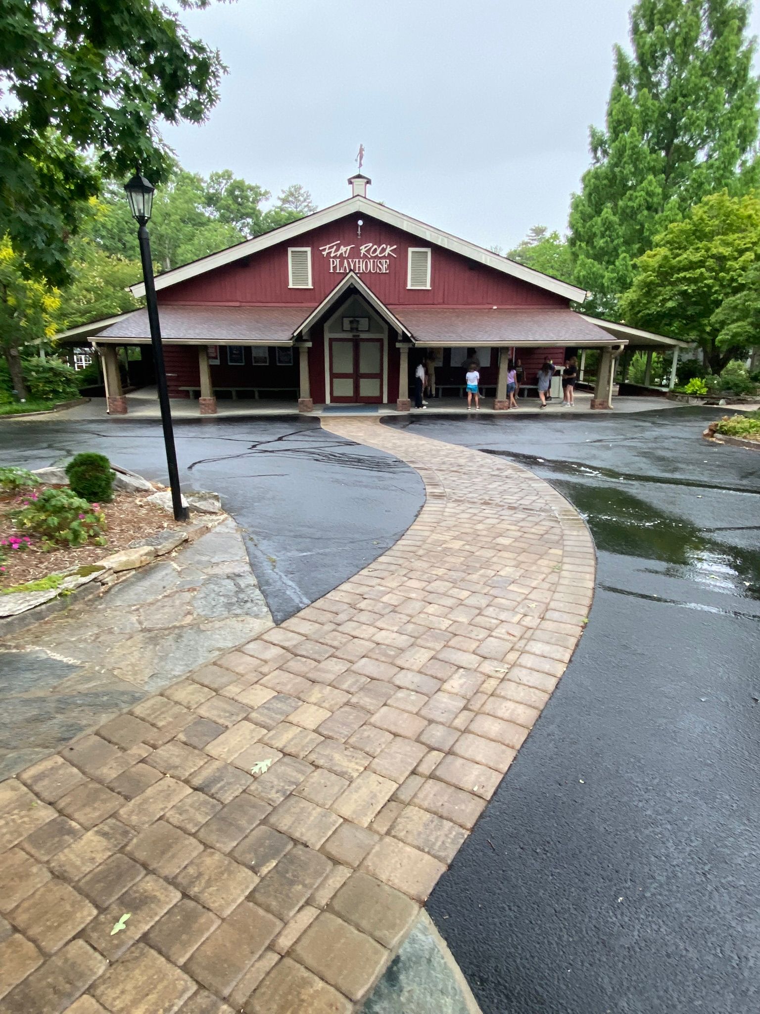 A large red barn with a brick walkway leading to it.