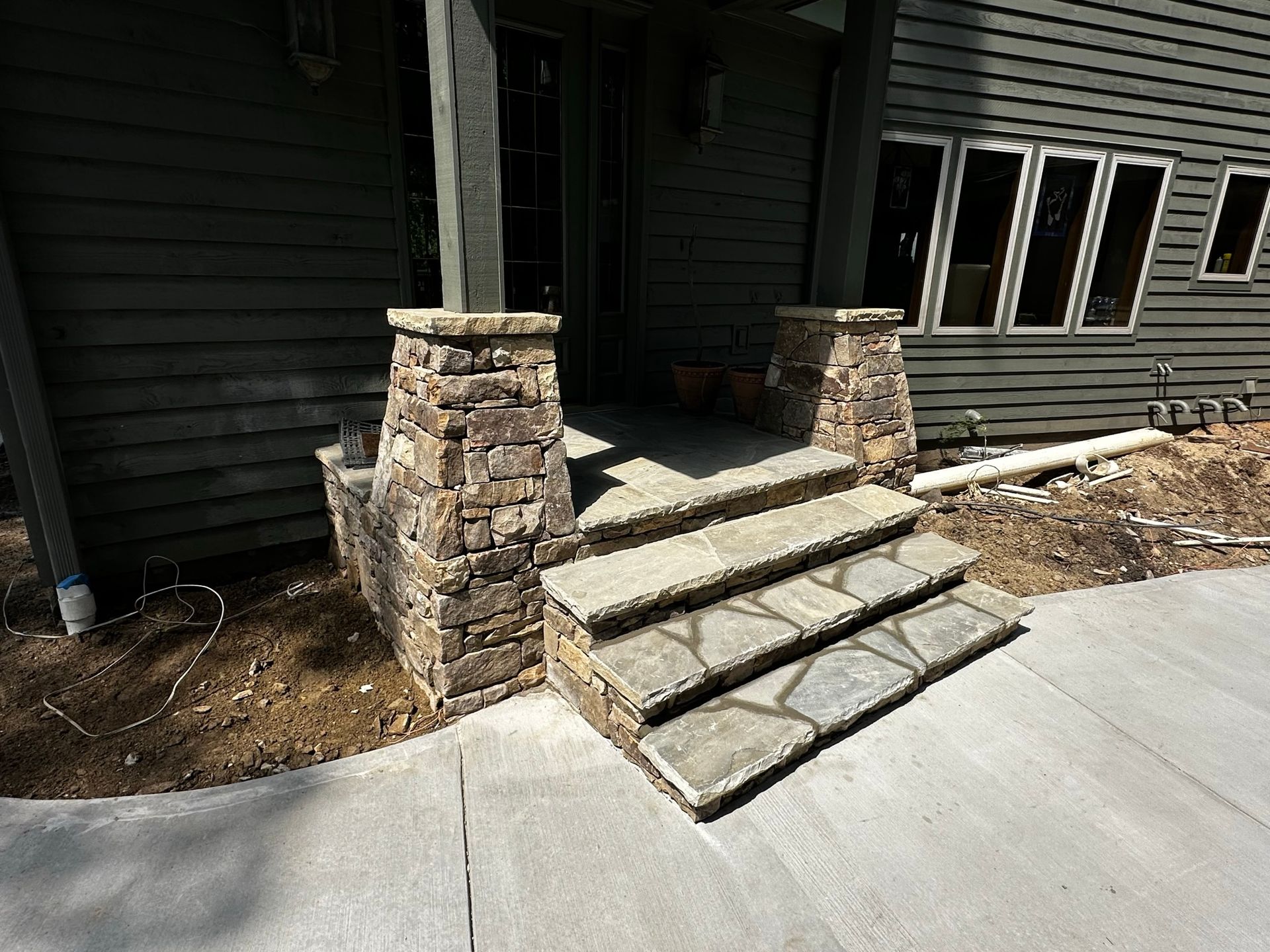 A stone porch with steps leading up to the front door of a house.