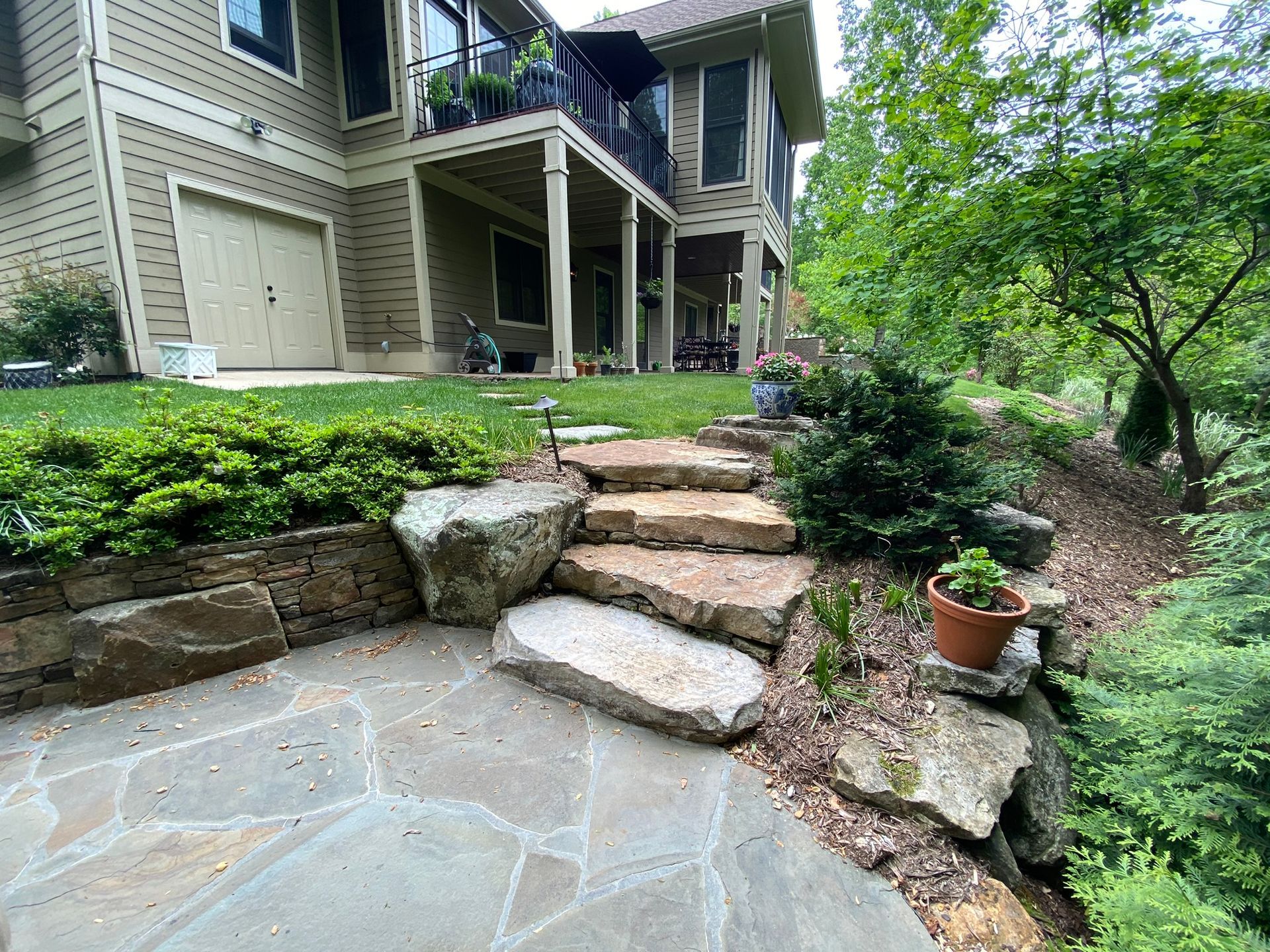 A stone walkway leading to a large house with stairs leading up to it.