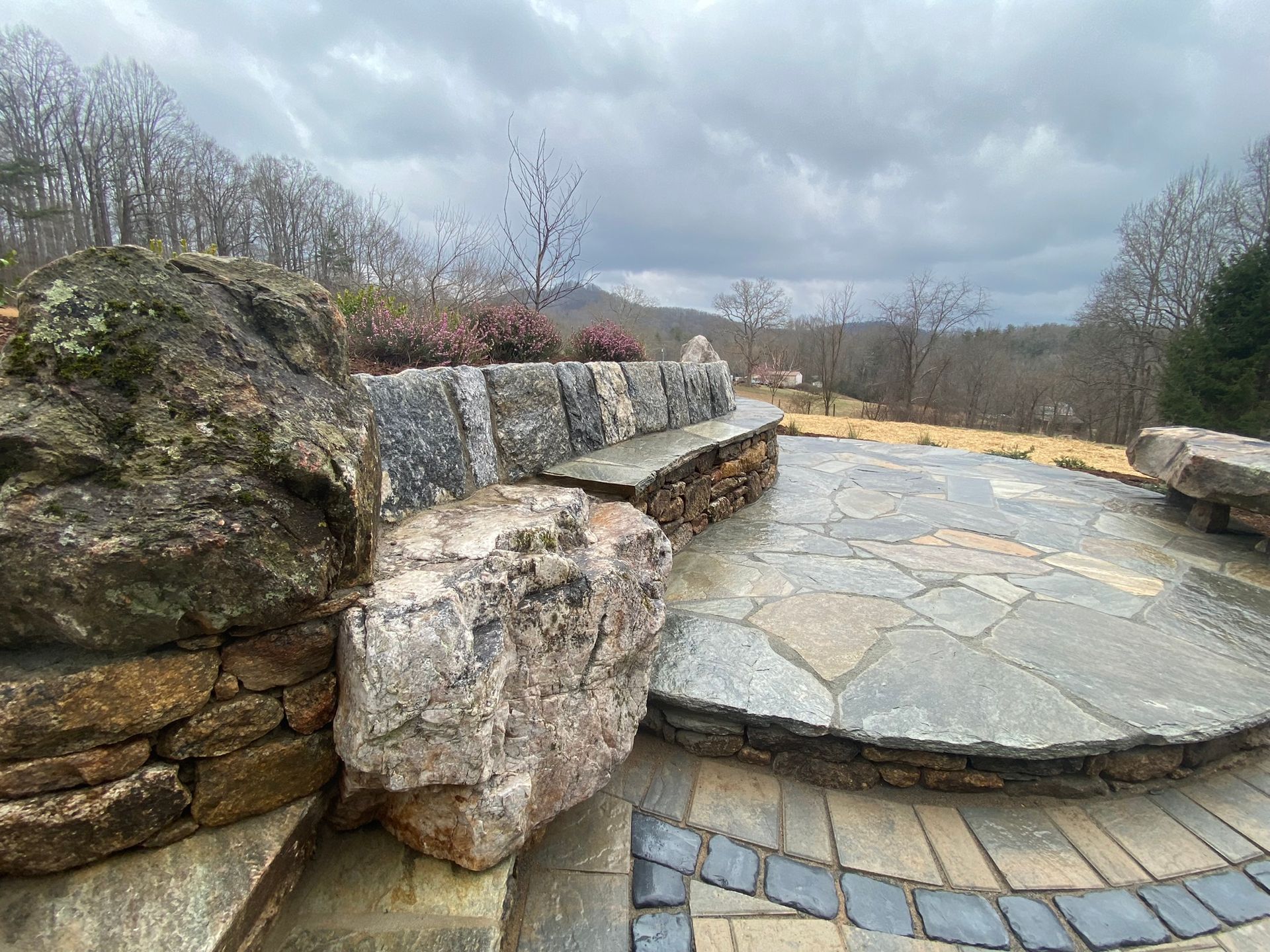 A stone patio with a stone wall and a stone bench.
