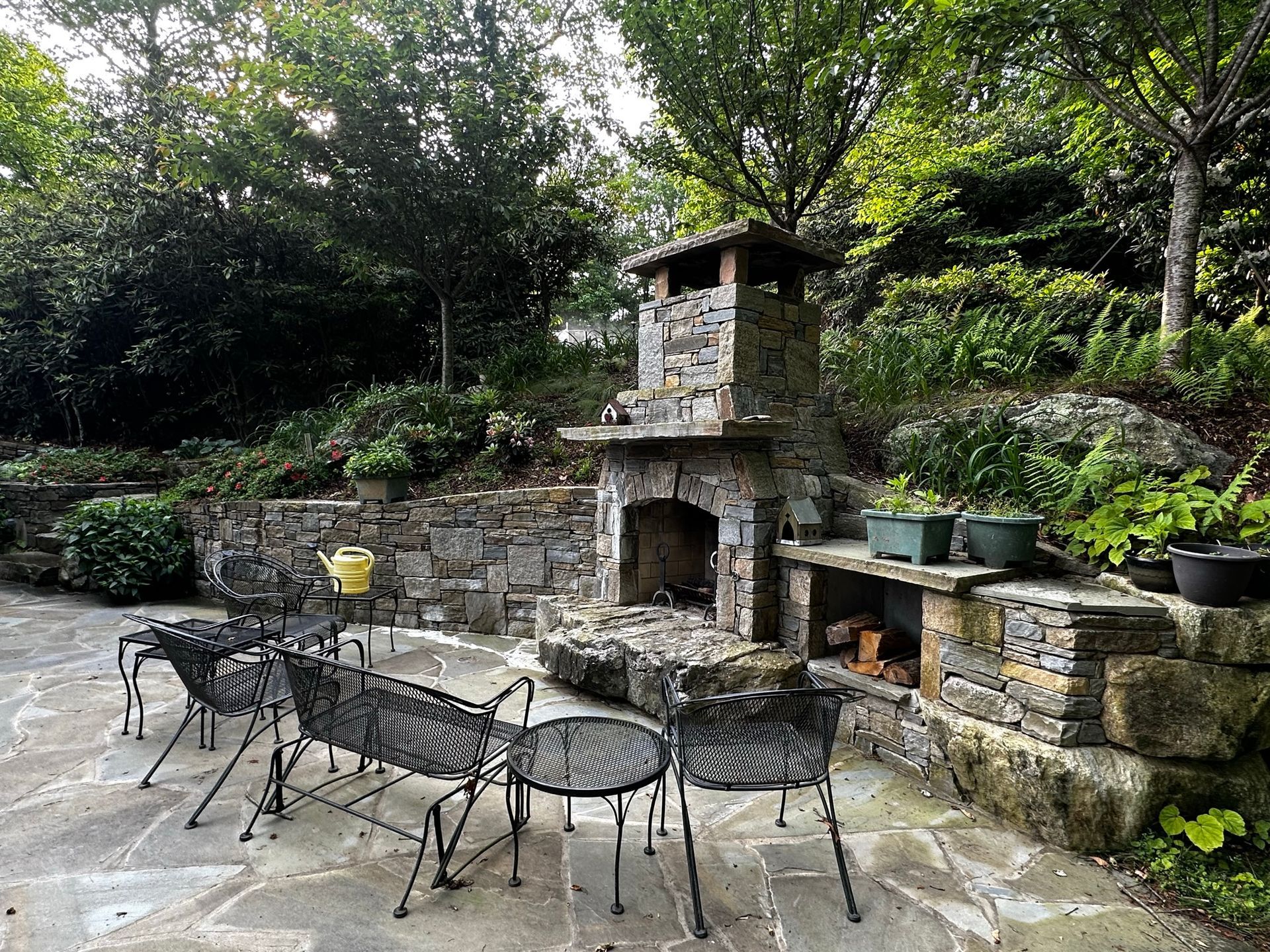 There is a fireplace in the backyard with a table and chairs.