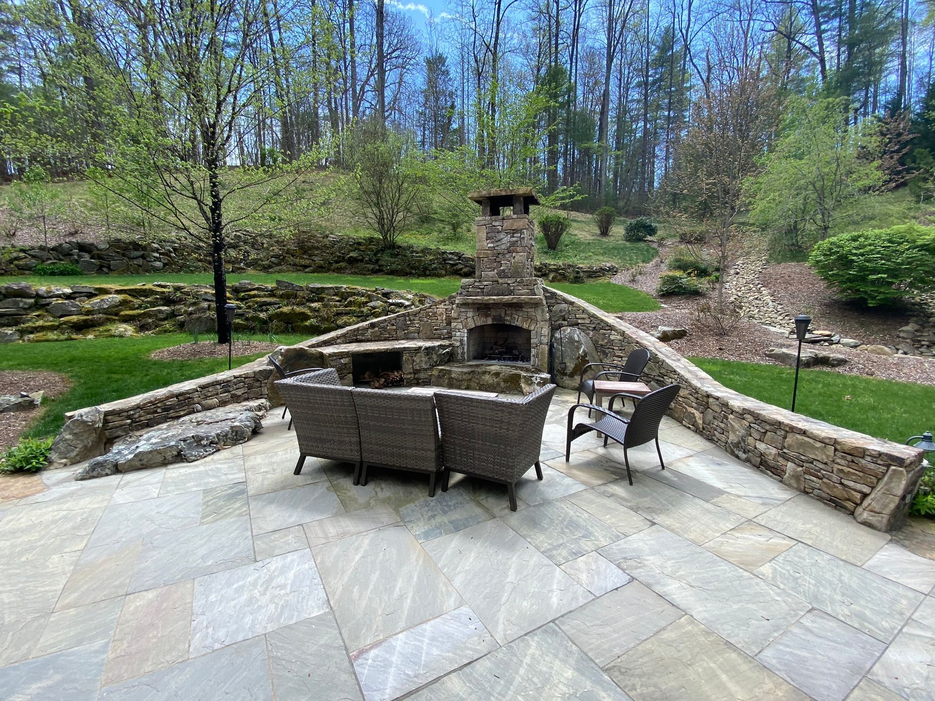 A patio with a fireplace and a couch and chairs.