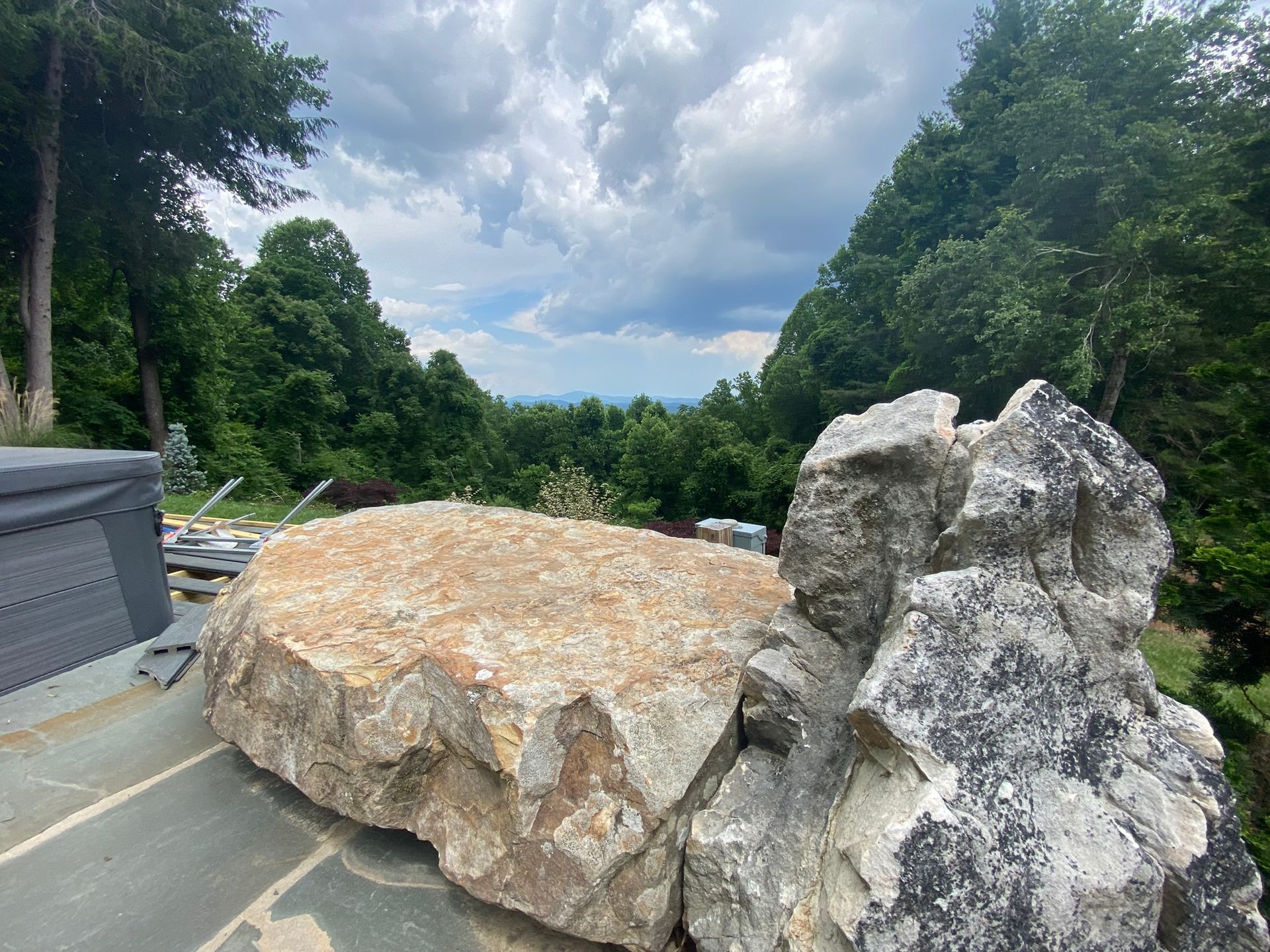 A large rock is sitting on top of a patio next to a hot tub.
