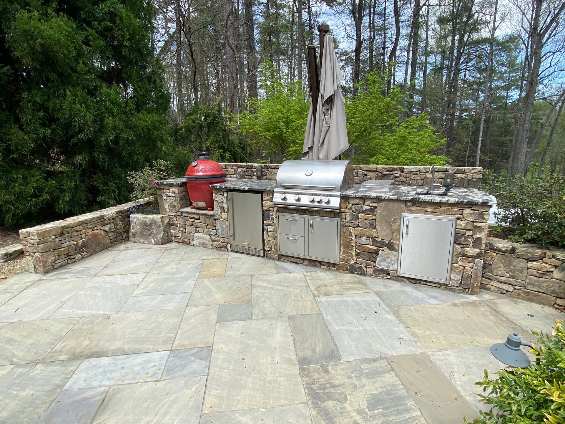 A large outdoor kitchen with a grill and umbrella