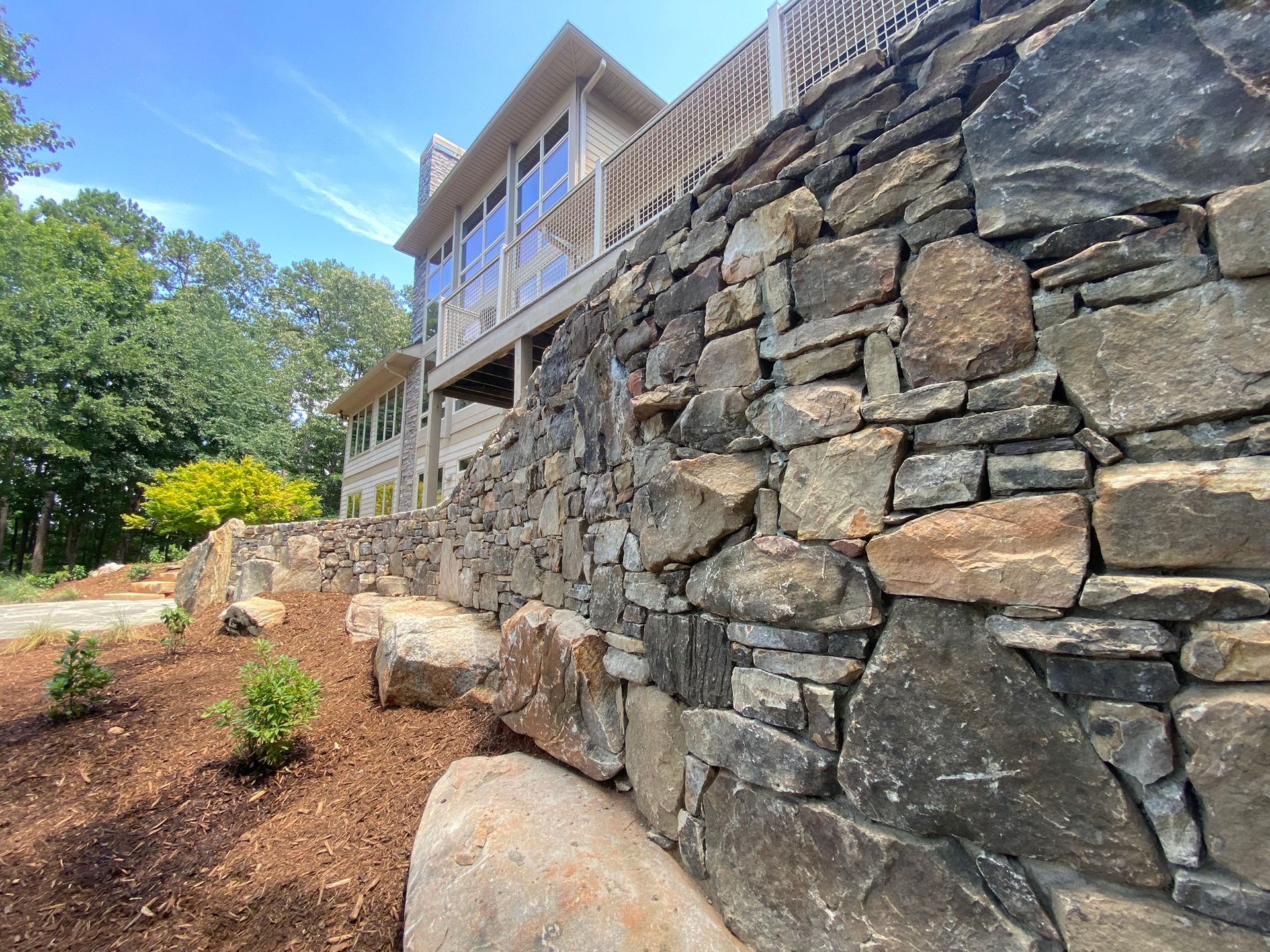 A large stone wall with a house in the background.
