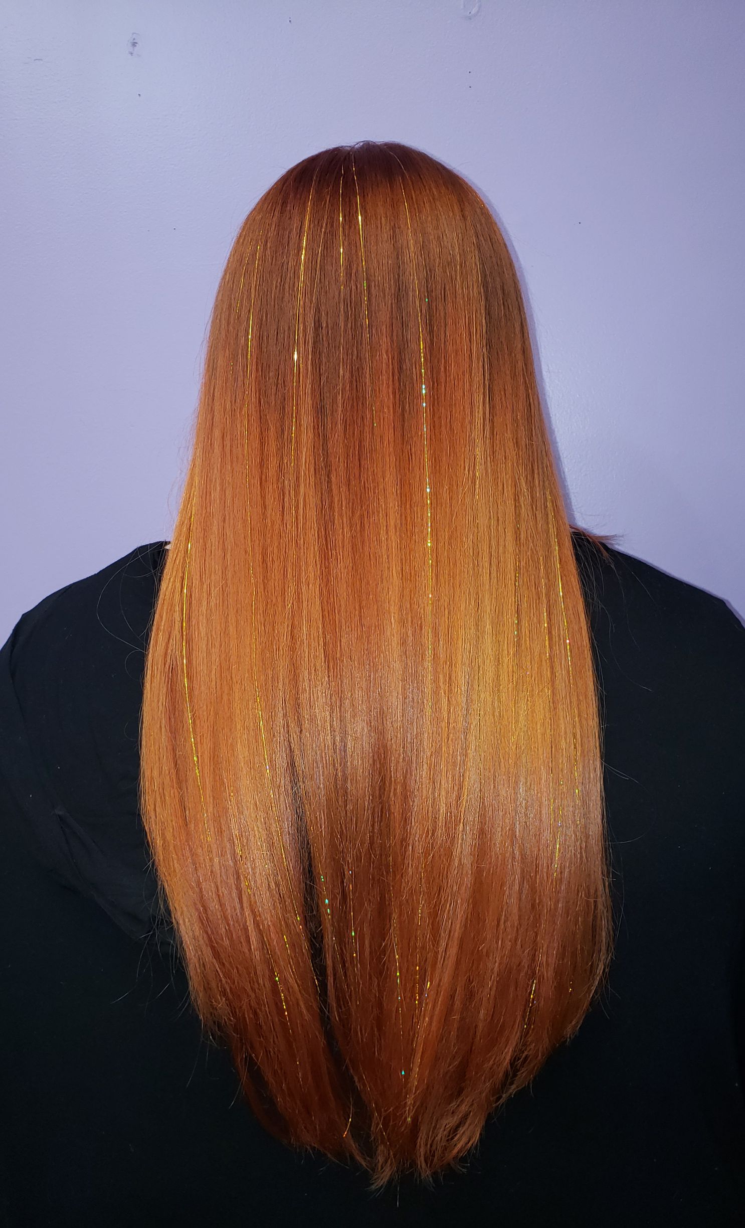 The back of a woman's head with long red hair and gold glitter.