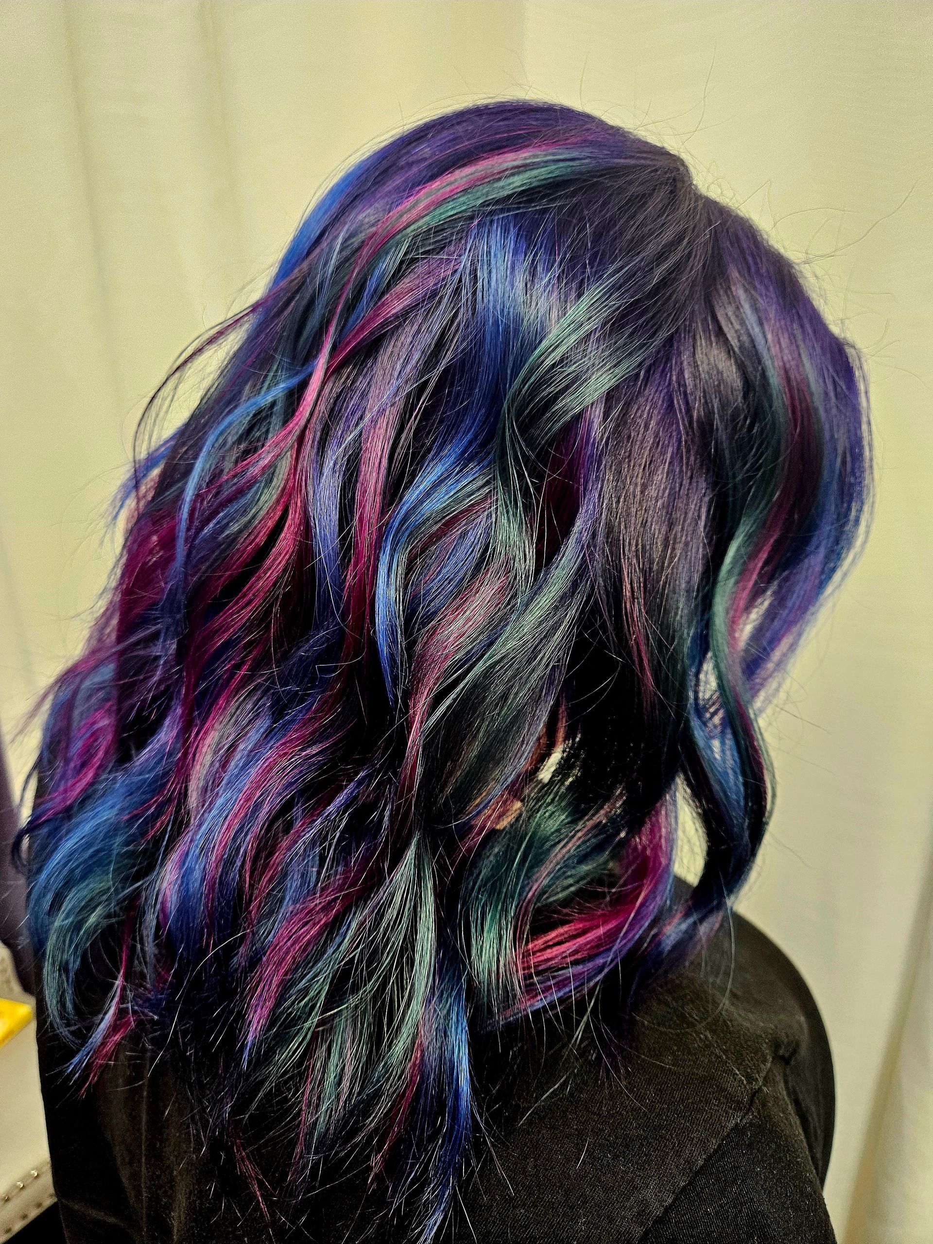 A woman with purple and blue hair is wearing a black shirt.