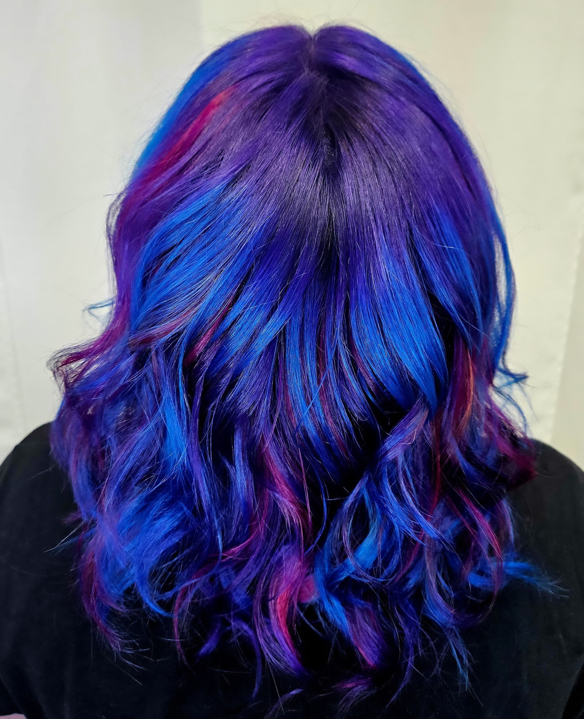 A woman with blue and purple hair is wearing a black shirt.