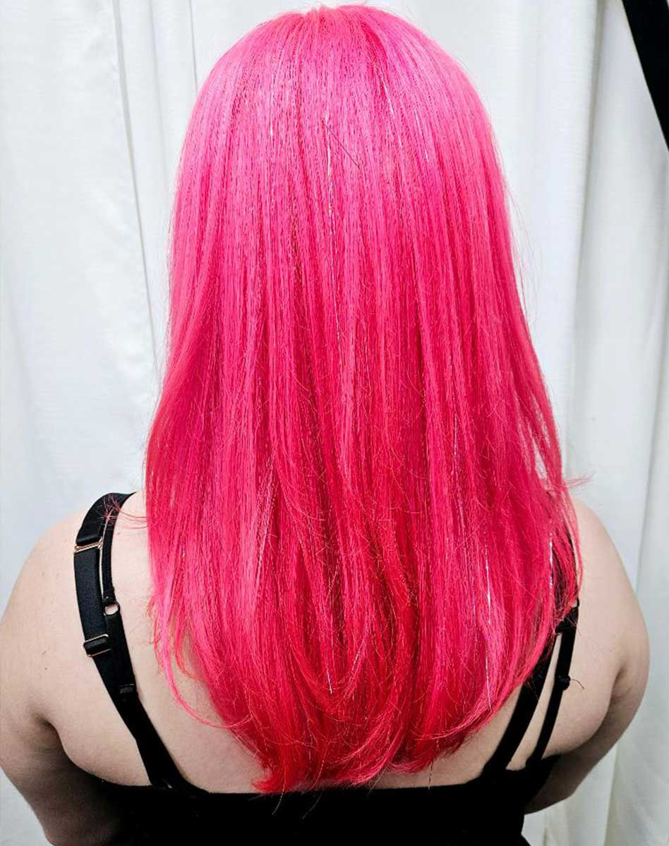 A woman with bright pink hair is wearing a black tank top.