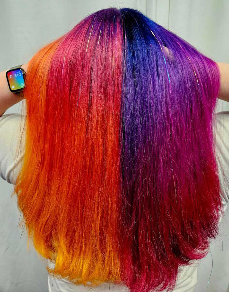 A woman with long colorful hair is wearing a watch.