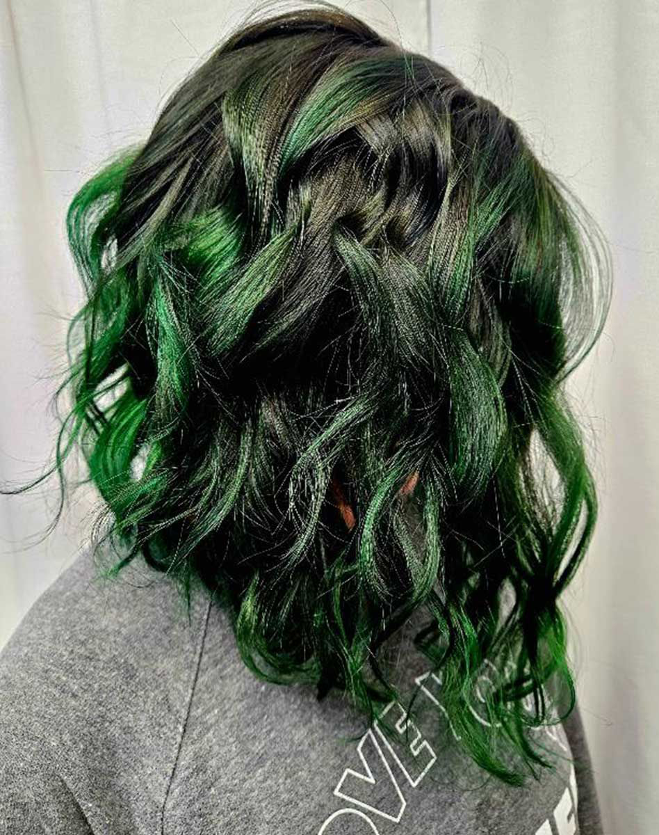 A woman with green hair is wearing a gray sweatshirt.