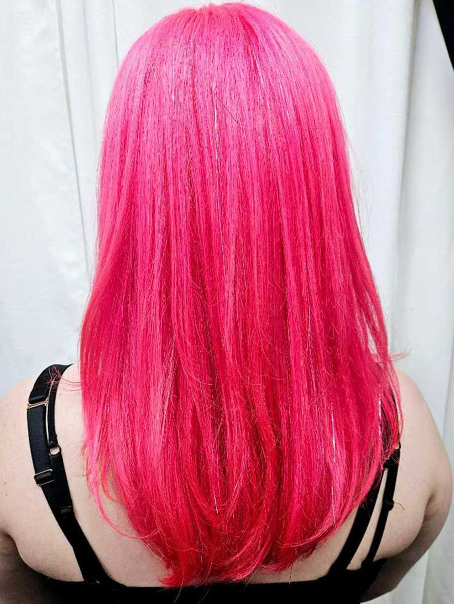A woman with bright pink hair is wearing a black bra.