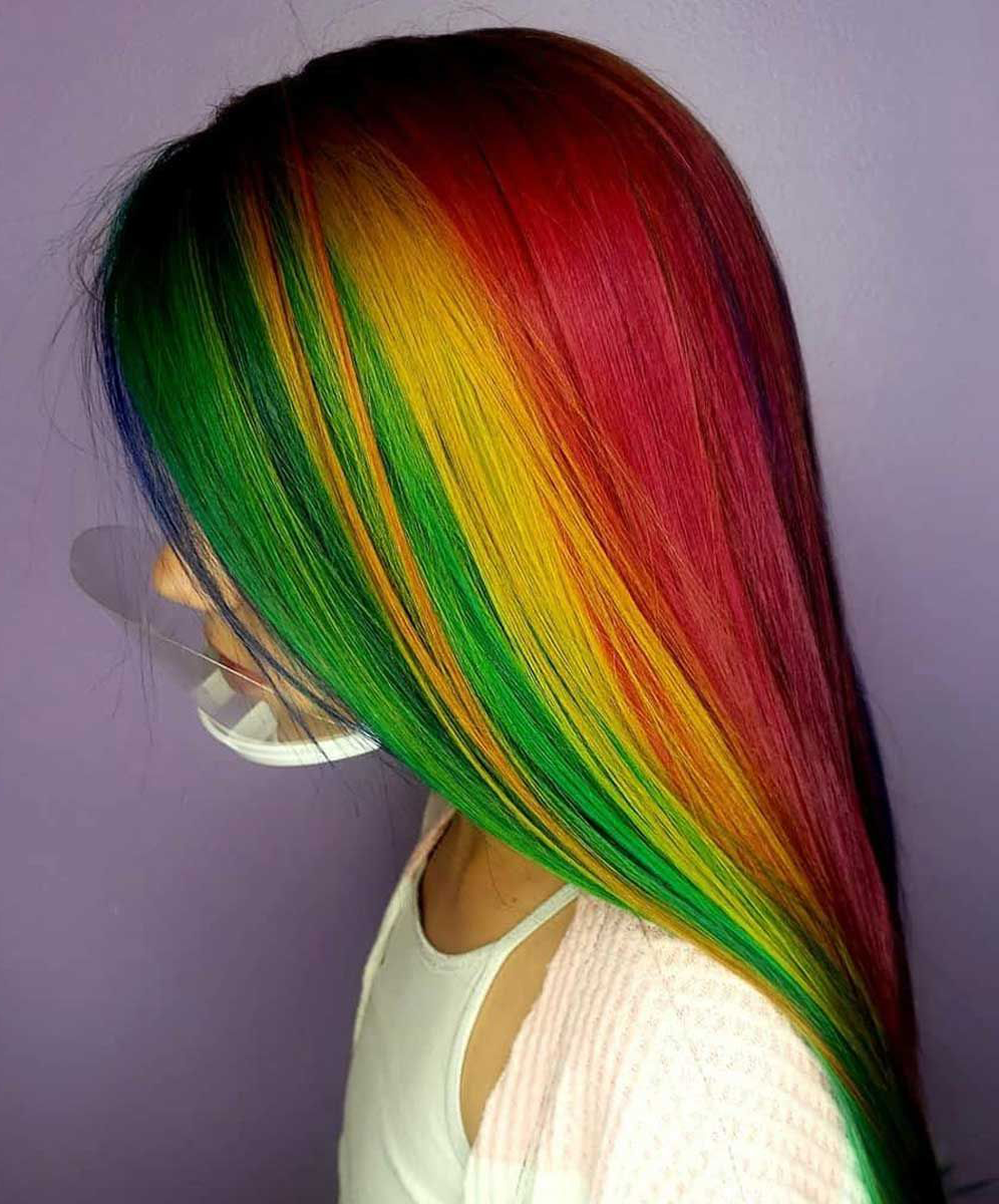 A woman with long rainbow hair is wearing a mask.