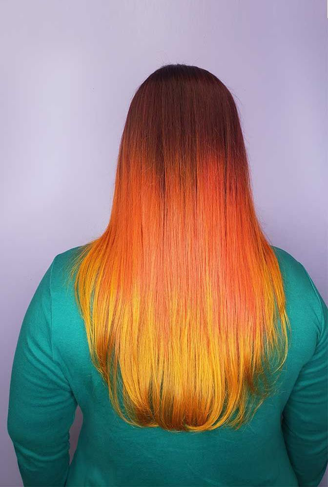 A woman with long orange and yellow hair is wearing a green shirt.