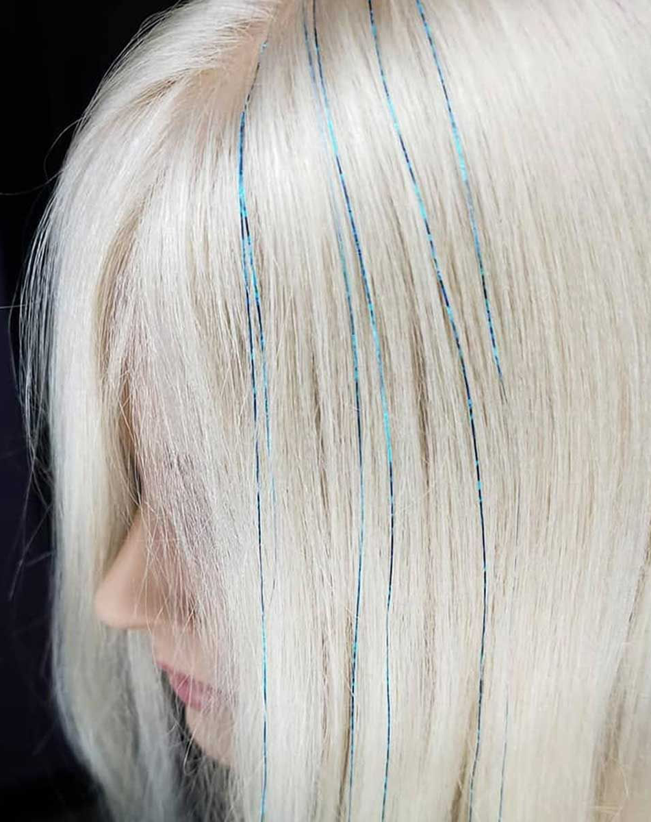 A close-up of a woman's blonde hair with hair tinsel.