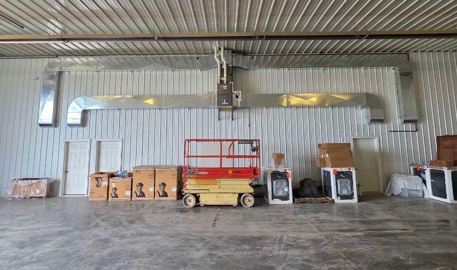 Empty industrial warehouse with stacked boxes, machinery, and a red scissor lift on a concrete floor