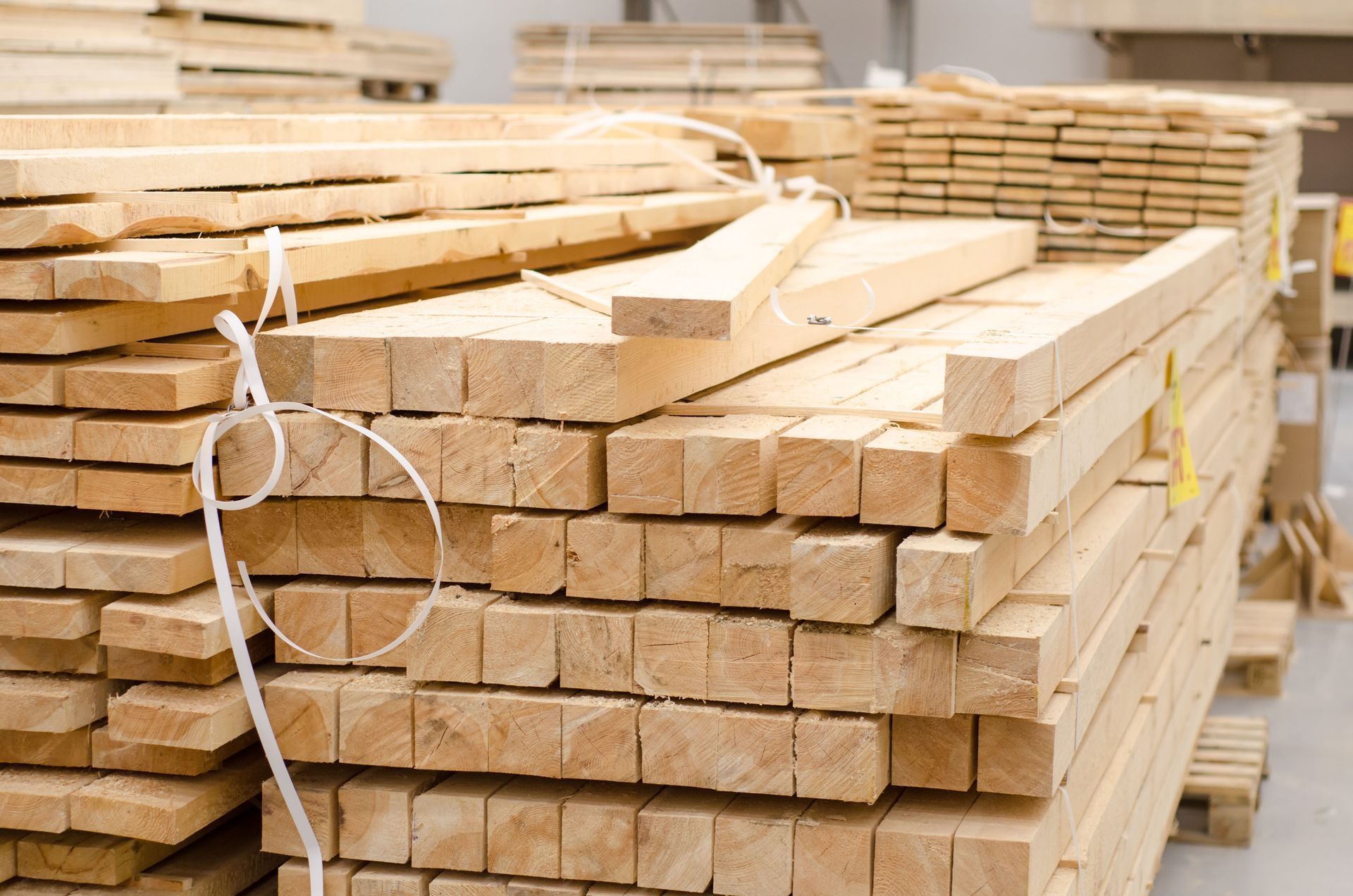 Stacks of cut lumber boards piled in a warehouse or lumber yard.