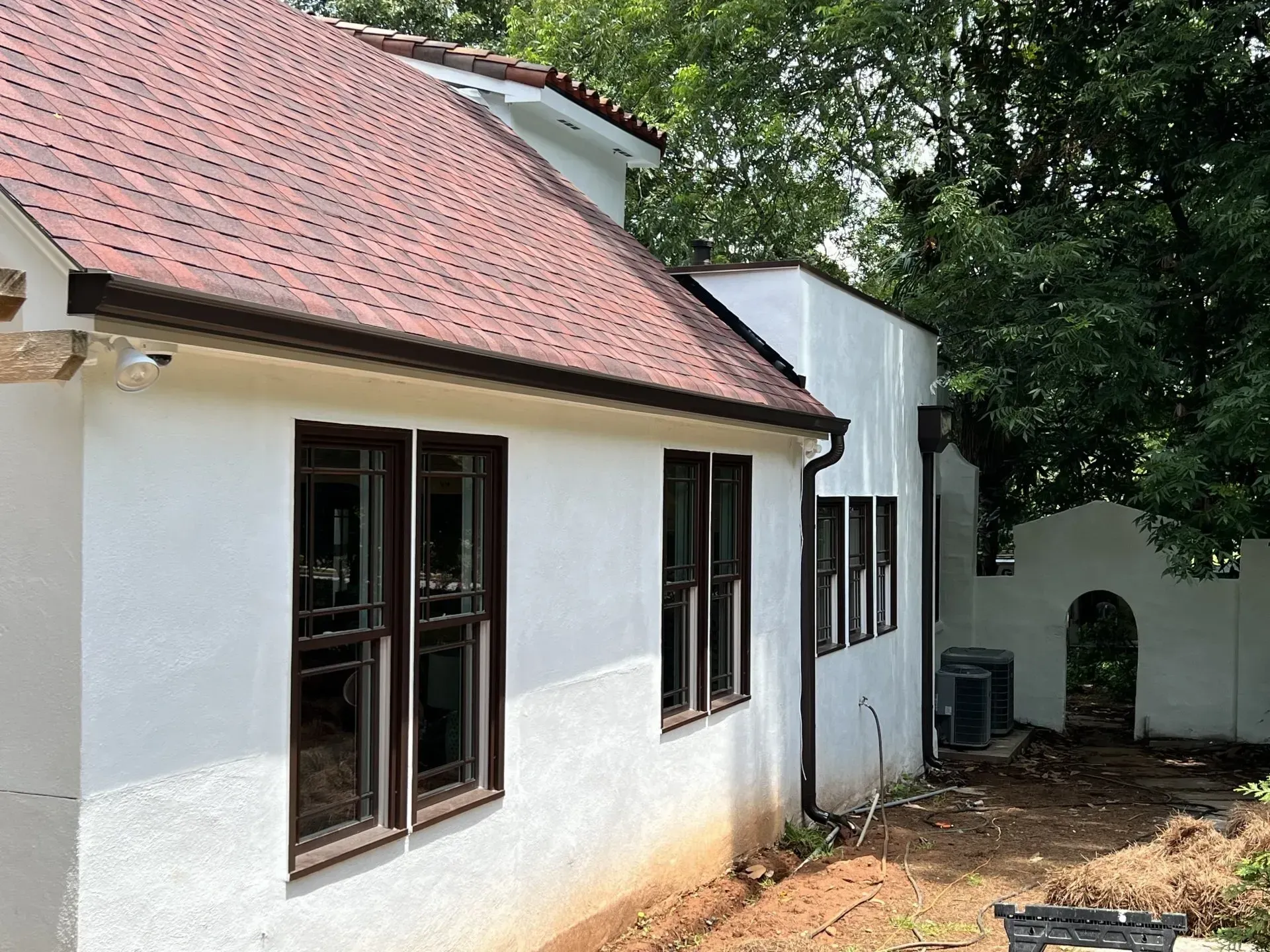 White stucco house with brown windows and terracotta tile roof.
