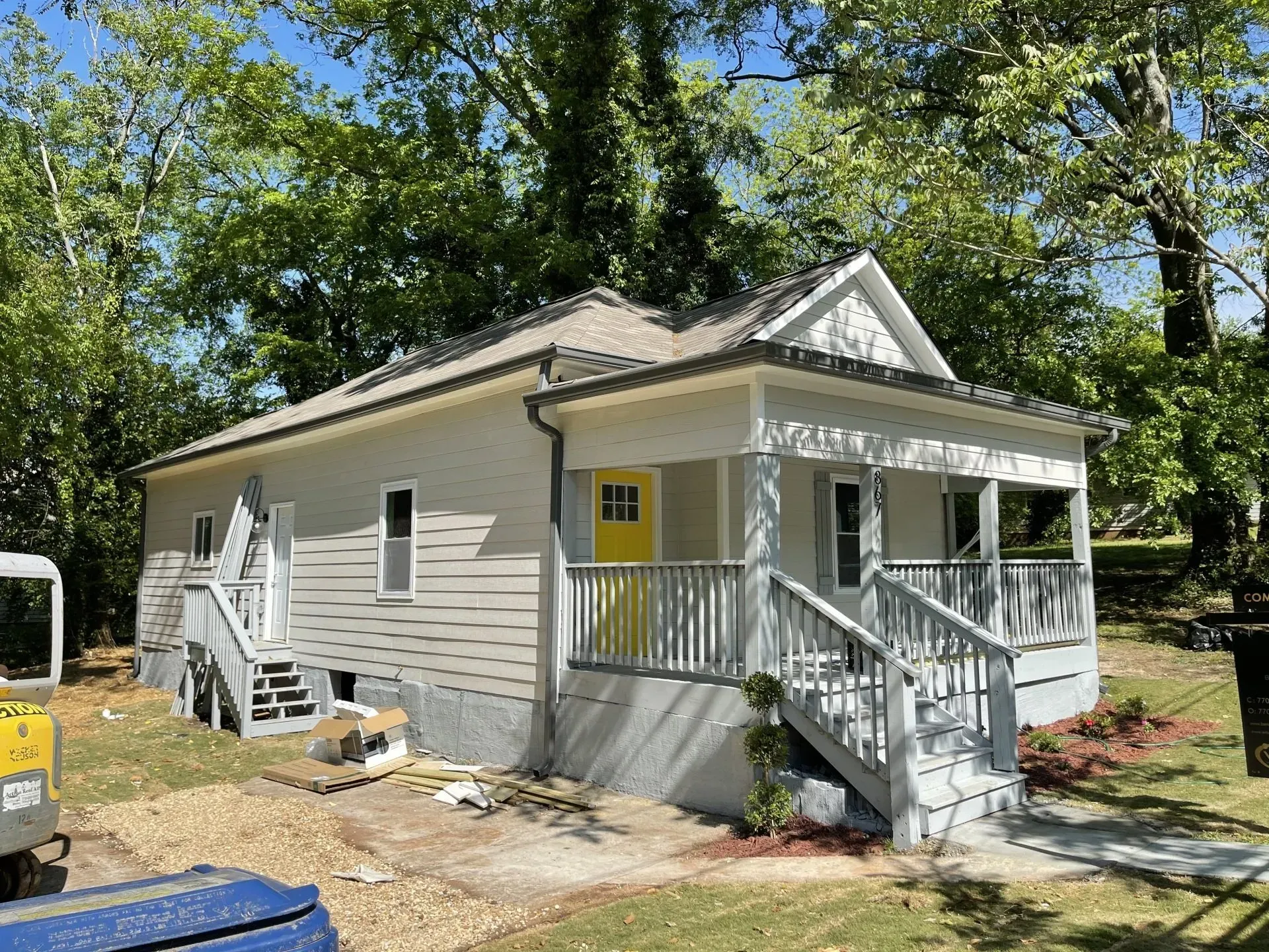 Small house with gray siding, white trim, and yellow door; porch with steps.