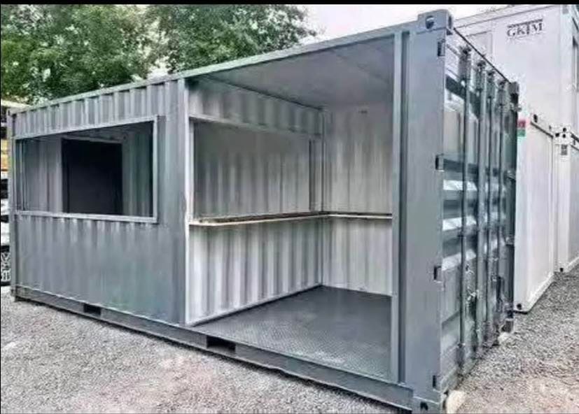 A gray shipping container modified with a large service window and open side for use as a retail or food kiosk.