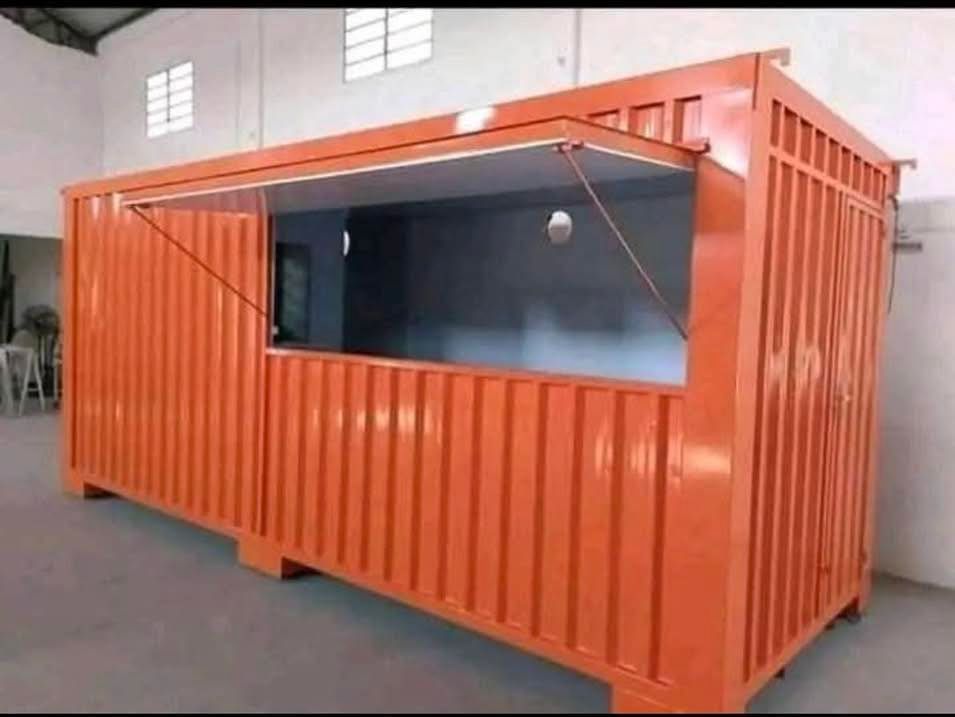 An orange shipping container converted into a food stall or kiosk with a wide, open service window.
