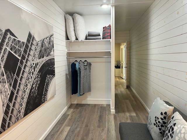 An open closet with shelves and clothes hangers beside a wall with a large black-and-white Eiffel Tower print.