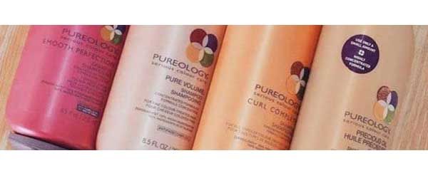 Three bottles of pureology hair products are lined up on a table.