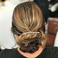 A woman is wearing a bun with a comb in her hair.