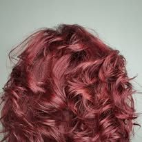 A close up of a woman 's red curly hair against a white background.
