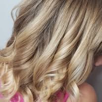 A close up of a woman 's blonde hair with curls.