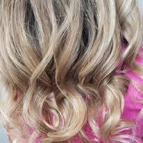 A close up of a woman 's blonde hair in a pink dress.