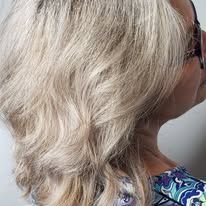 A woman with blonde hair and glasses is wearing a floral shirt.