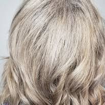 A close up of a woman 's blonde hair on a gray background.
