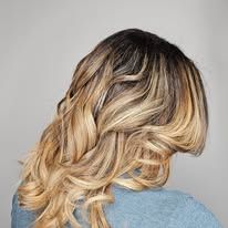 A woman with long blonde hair is wearing a blue sweater.