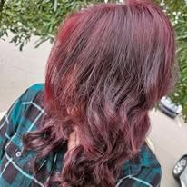 A woman with purple hair is wearing a plaid shirt.