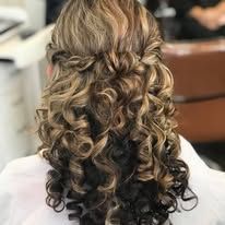 A woman with curly hair is wearing a half up half down hairstyle.