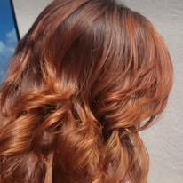 A woman with long red hair is wearing her hair in a half up half down hairstyle.