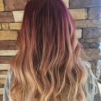 A woman with long red hair is standing in front of a brick wall.