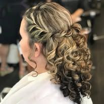A woman with curly hair is getting her hair done in a salon.