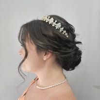 The woman is wearing a tiara and a pearl necklace.