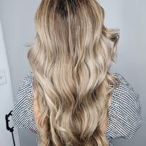 A woman with long blonde hair is wearing a plaid shirt.