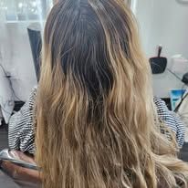 A woman with long blonde hair is sitting in a chair in a salon.