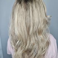 A woman with long blonde hair is wearing a pink shirt.