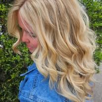 A woman with long blonde hair is wearing a denim jacket.