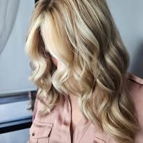 A woman with long blonde hair is wearing a pink shirt.