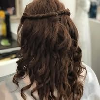 A woman with long brown hair is wearing a braided half up half down hairstyle.