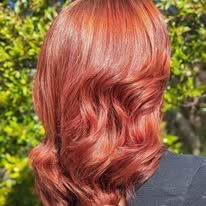 A woman with long red hair is wearing a black shirt.