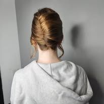 The back of a woman wearing a gray sweatshirt and a bun.