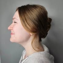A woman with her hair in a bun is smiling.