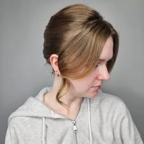 A woman in a grey hoodie with her hair in a bun.